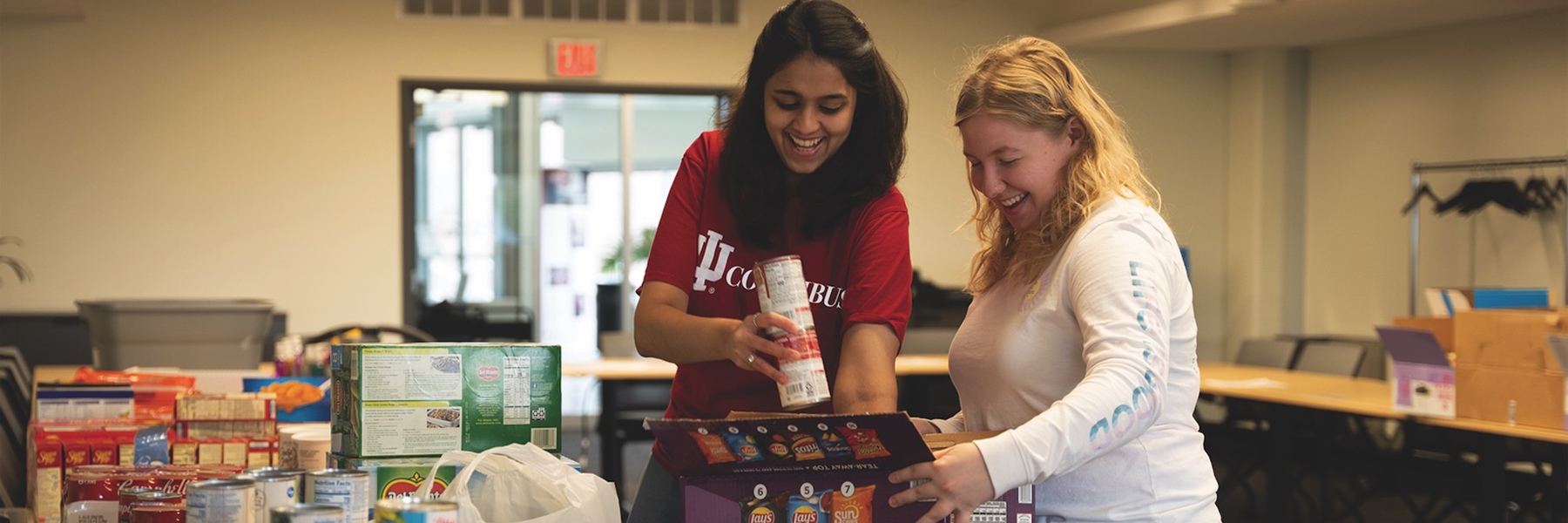 Two women sorting goods in the pride pantry